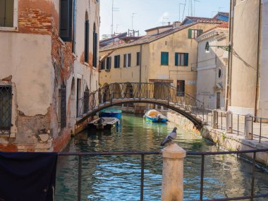 Venedik, İtalya. 28.10.2022 Venedik 'in en popüler turizm merkezi değil. Şehrin varoşlarında. Kanallar, evler ve köprüler. geleneksel pencereli düşük pembe evler