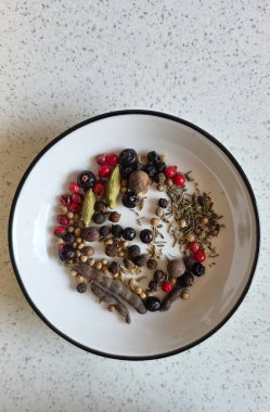 Yuvarlak bir kasede, açık dokulu bir tezgahın üzerinde güzelce dizilmiş baharatlar ve otlar..