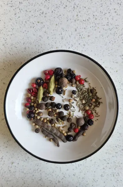 Yuvarlak bir kasede, açık dokulu bir tezgahın üzerinde güzelce dizilmiş baharatlar ve otlar..