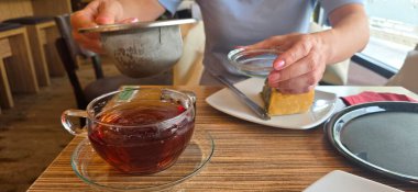 Çayı cam bardakla, tatlıyı da kafeteryada, ahşap masada hazırlıyorum..