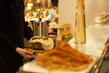Bilinmeyen adam sosisli hazırlıyor, popüler sokak yemekleri. Geleneksel soslar, mayonez, ketçap ve hardal. Amerikan sarısı hardallı sosisli sandviç ve kağıda sarılmış taze marul.