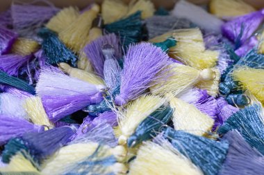 Mor, sarı ve yeşil tonlarda renkli püsküllerin canlı koleksiyonu, karmaşık dokular ve işçilik sergiliyor..