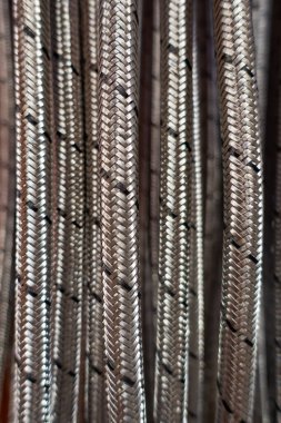 Örgülü metalik kabloların detaylı yakın çekimi, eşsiz dokularını ve desenlerini vurguluyor, endüstriyel bir arka plana karşı kurulmuş..