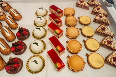 Beyaz bir yüzeye yerleştirilmiş çeşitli gurme hamur işleri. Karmaşık tasarımlar ve canlı renkler..