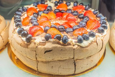 Katmanlı pasta taze çilek ve yaban mersini içeriyor, üzerinde güzel bir şekilde düzenlenmiş, canlı renkler ve çekici dokular sergiliyor..
