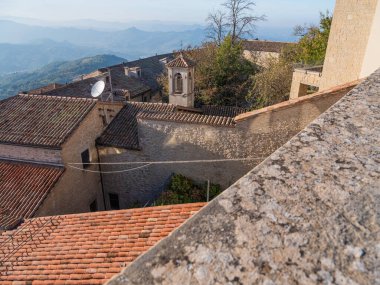 San Marino Cumhuriyeti. Dağdaki 31.10.2022 antik kale. Dar sokaklar turist, restoran ve hediyelik eşya dükkanlarıyla dolu. Aşağıda gün batımında güzel bir dağ manzarası var.