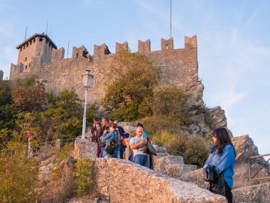 San Marino Cumhuriyeti. Dağdaki 31.10.2022 antik kale. Dar sokaklar turist, restoran ve hediyelik eşya dükkanlarıyla dolu. Aşağıda gün batımında güzel bir dağ manzarası var.