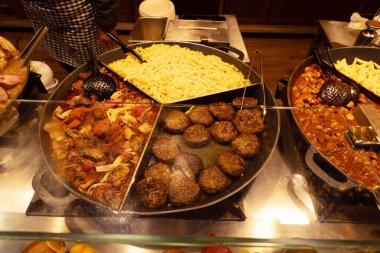 Makarna, et köfteleri ve aromalı kenarları da dahil olmak üzere çeşitli pişirilmiş yemeklerden oluşan canlı bir açık büfe..