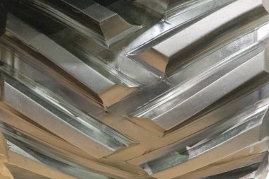 Metalik yüzeyin detaylı yakın çekimi eşsiz doku ve desenleri sergiliyor, ışığı güzel yansıtıyor, dinamik bir görsel deneyim yaratıyor..