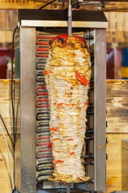 Dikey rosto, baharatlı et ve canlı sebze katmanları sergiliyor, iştah açıcı sokak yemekleri hazırlıyor..