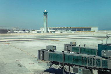 Doha, Katar - 02 Şubat 2023: Gökyüzü altında kontrol kulesi ve jet köprüleri bulunan havaalanı terminali.