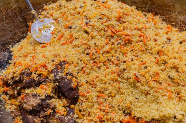 Etli ve sebzeli canlı pirinç tabağı, büyük bir tencerede sunuluyor, mutfak geleneği ve ortak paylaşım.