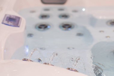 Çağdaş jakuzi sergilenen kabarcıklı jetler ve temiz su, rahatlama ve sağIık için tasarlanmış, sakin bir atmosfer yaratıyor..