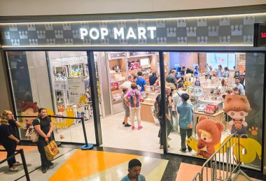 Berlin, Almanya. 27 Ağustos 2025. Market içi ziyaretçileri bakınıyor. Raflarda koleksiyon figürleri ve ürünler sergilenirken, cam anonslarda satılan Labubu serileri çeşitli tabelalar yer alıyor.