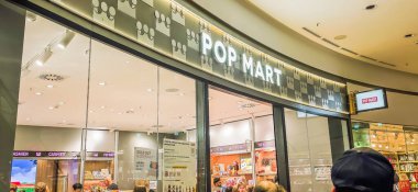 Berlin, Almanya. 27 Ağustos 2025. Market içi ziyaretçileri bakınıyor. Raflarda koleksiyon figürleri ve ürünler sergilenirken, cam anonslarda satılan Labubu serileri çeşitli tabelalar yer alıyor.