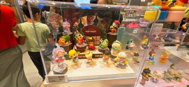 Berlin, Almanya. 27 Ağustos 2025. Market içi ziyaretçileri bakınıyor. Raflarda koleksiyon figürleri ve ürünler sergilenirken, cam anonslarda satılan Labubu serileri çeşitli tabelalar yer alıyor.