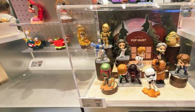 Berlin, Almanya. 27 Ağustos 2025. Market içi ziyaretçileri bakınıyor. Raflarda koleksiyon figürleri ve ürünler sergilenirken, cam anonslarda satılan Labubu serileri çeşitli tabelalar yer alıyor.