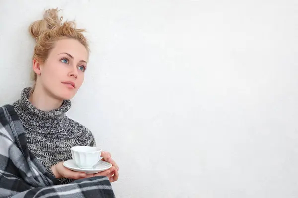 一个年轻的女人享受片刻的放松 坐在地板上 靠着一面白色的墙 喝一杯咖啡或茶 生活方式或与饮料有关的概念的平静和舒适的气氛 免版税图库图片
