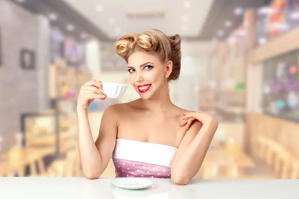 一位年轻貌美的女士 有着20世纪50年代的美式发型 愉快地喝茶 完美的复古主题概念和表达永恒的优雅 图库照片