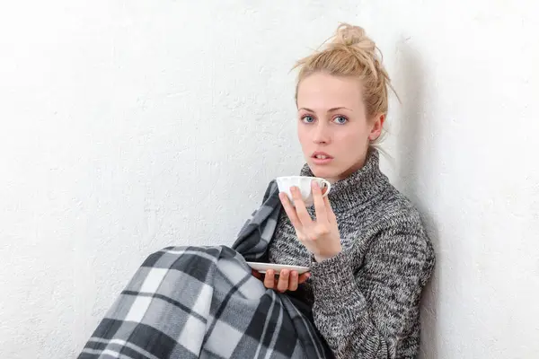 一个年轻的女人享受片刻的放松 坐在地板上 靠着一面白色的墙 喝一杯咖啡或茶 生活方式或与饮料有关的概念的平静和舒适的气氛 图库图片
