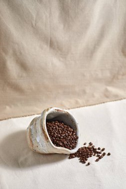 Spilled coffee beans from ceramic on  textile background.selective focu