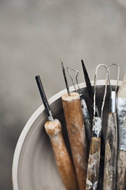 Tools for forming clay with pots in background , selective focus clipart