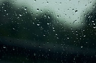 Pencereye yağmur damlıyor, ağaçlar ve yapraklar dışarıda. seçici odak