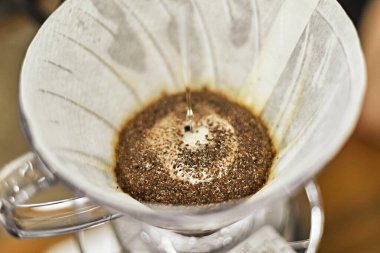 Alternatif kahve demleme metodu, damlatıcı ve kağıt filtresinin üzerine dökülüyor.