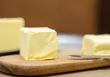 Bir kalıp tereyağını doğrama tahtasına yakın çekim, bulanık arkaplan