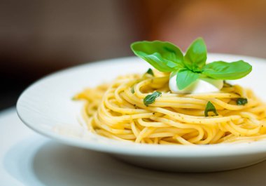 Krema soslu İtalyan makarnası ve fesleğen, bulanık arka plan.