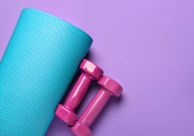 Mor arkaplanda yoga minderi ve halterler