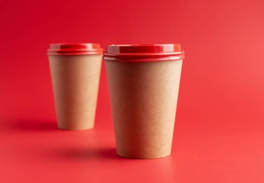 Kırmızı arka planda sıcak içecekler için kağıt bardak.