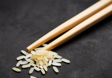 Koyu arkaplanda pirinç taneli ahşap çubuklar.