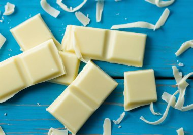 Mavi ahşap arka planda beyaz çikolata parçalarının yakınlaştırılması