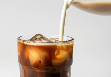 Buzlu kahvenin üzerine süt döküldü.