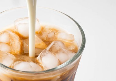 Buzlu kahvenin üzerine süt döküldü.