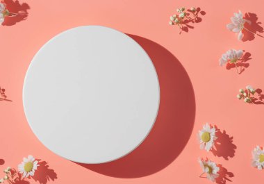 Pembe mercan renginde beyaz podyum açık renk gölgeler ve bahar çiçekleri, minimalist düz zemin, üst hayat