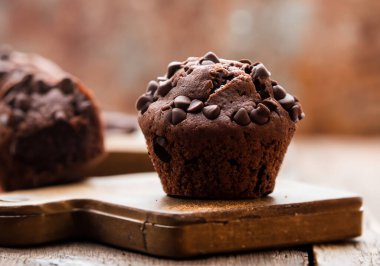 Eski bir ahşap masa üzerinde çikolata parçalı kek, bulanık arka plan.