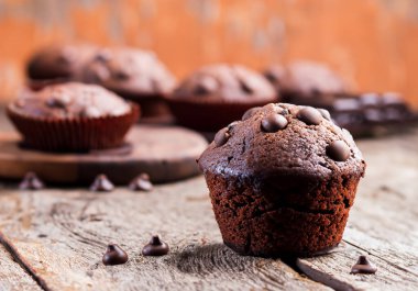 Eski bir ahşap masa üzerinde çikolata parçalı kek, bulanık arka plan.