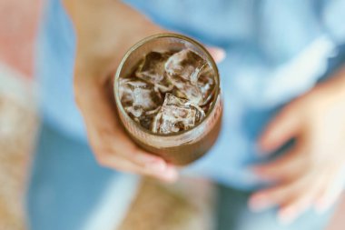 Hand 'in elinde bir bardak buzlu Americano ya da sırt kahvesi tutarken yaklaş.