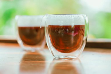 Kırmızı çay ya da Ejderha kanı çayı. Tahta masadaki küçük, berrak bardakta.