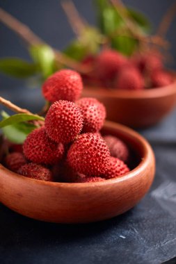 Koyu arkaplanda yaprakları olan taze kırmızı liçi meyveleri..