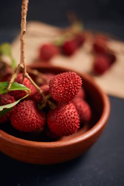 Koyu arkaplanda yaprakları olan taze kırmızı liçi meyveleri..