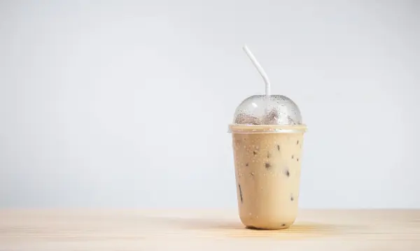 Iced coffee or coffee latte in takeaway cup on wooden table. coffee package for takeaway, Cold beverage product.