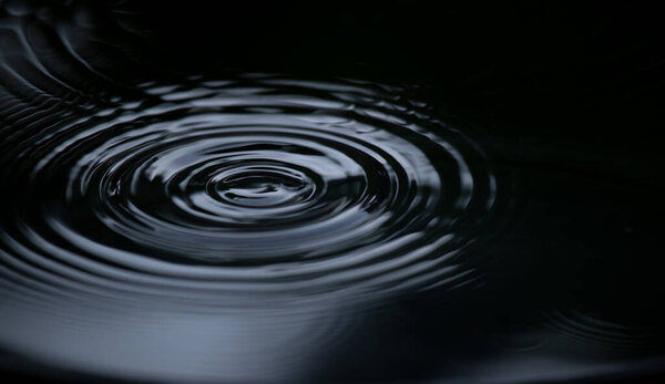 Ripple of water or water drop splash on black background. Abstract shape out of the water