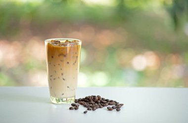 Sütlü kahve bardakları beyaz masada kahve çekirdekleri. Soğuk içecek lezzetli. Buzlu latte..