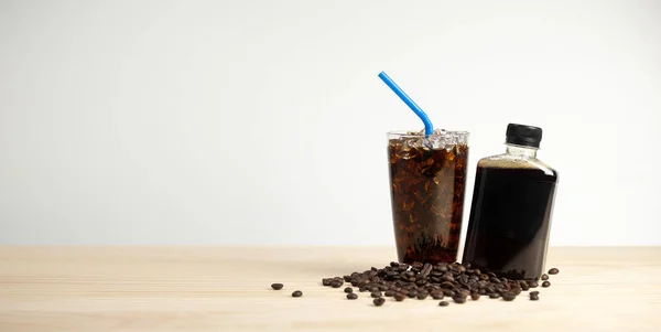 Iced americano coffee with coffee beans on grey background, Black coffee glass package for takeaway. Cold beverage product.