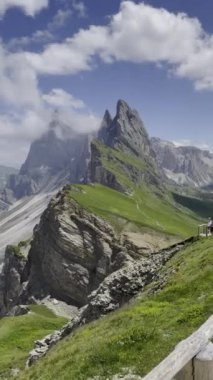 Dolomite tepelerinin ve mavi gökyüzünün altındaki yemyeşil tepelerin çarpıcı manzarası. Dikey video. İtalyan Dolomitler.