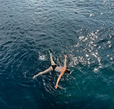 Bir yüzücü, okyanusların sakin yüzeyinde huzur içinde yüzer.
