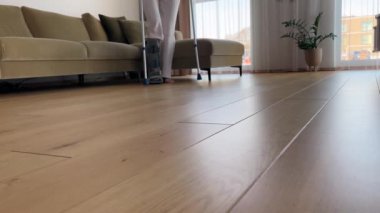 Bacağı alçılı bir kadın oturma odasındaki kanepeden kalkar ve yavaşça ileri doğru yürür..